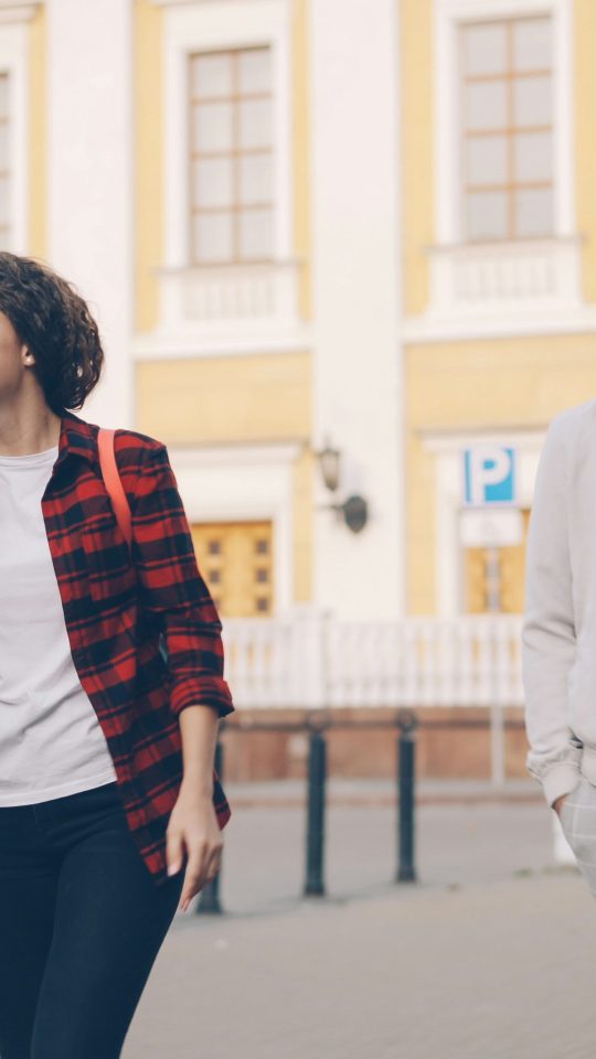 Friends are walking and smiling together outdoors.